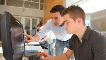 lærer hjælper ung studerende ved computer