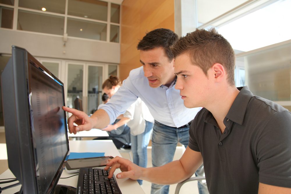 lærer hjælper ung studerende ved computer