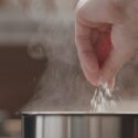 Hånd hælder salt i gryde