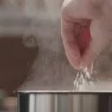 Hånd hælder salt i gryde