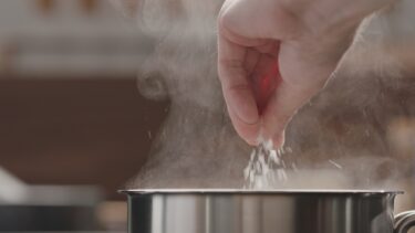 Hånd hælder salt i gryde