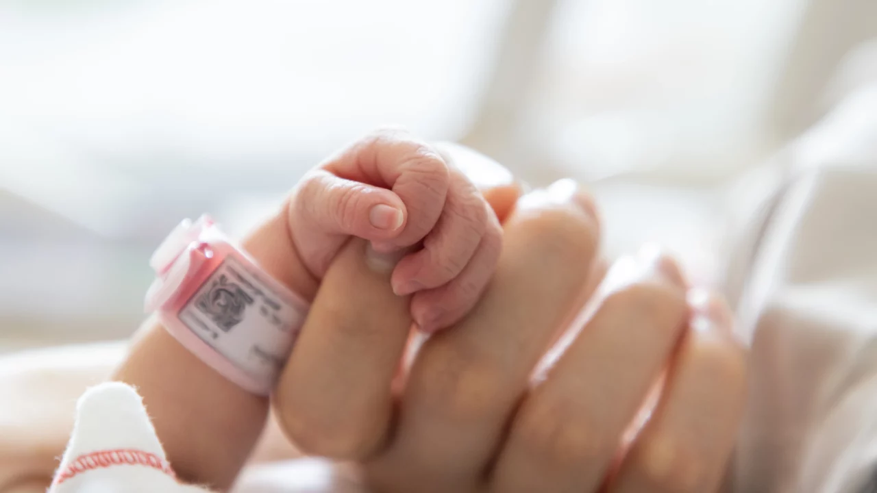 nyfødt holder om sin mors finger