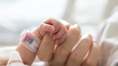 nyfødt holder om sin mors finger