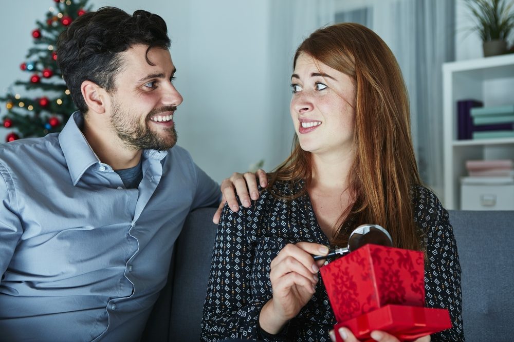 Par ved juletræet, kvinden har fået en gave, hun ikke er glad for, hun ser akavet ud i ansigtet