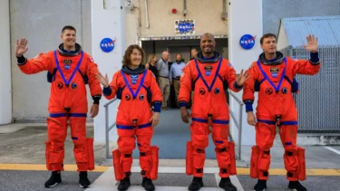 NASA-astronauter i orange rumdragter står foran NASA og vinker