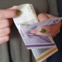 Kvindehænder bladrer mellem dansk 100-kroneseddel og halvtredskroneseddel