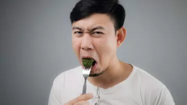 Mand spiser broccoli og skærer ansigt, kan ikke lide det