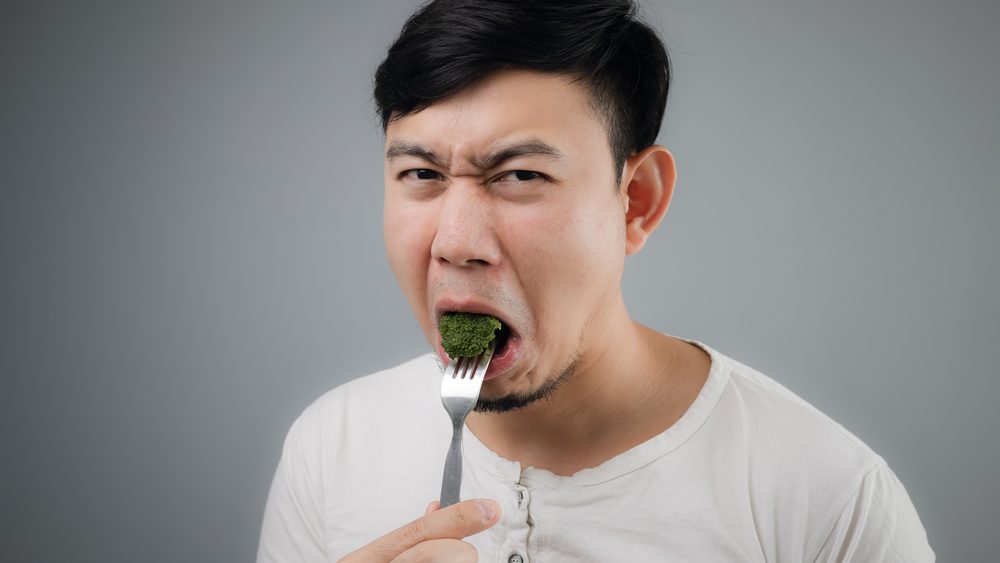 Mand spiser broccoli og skærer ansigt, kan ikke lide det