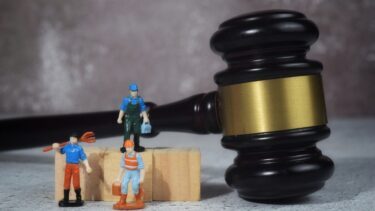 En hammer fra en domstol ved siden af tre figurer af arbejdsmænd.