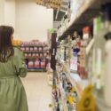 Ung kvinde går forbi alkoholhylde i et supermarked