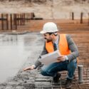 En arkitekt tilser et betonfundament på en byggeplads