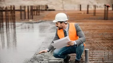 En arkitekt tilser et betonfundament på en byggeplads