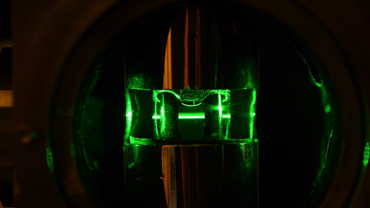 Grøn laser skyder gennem glas i mørke
