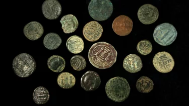 en samling gamle mønter fra romersk tid ligger spredt på en sort baggrund