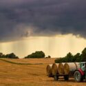 Foto af en mark i Jylland, hvor en traktor samler halmballer.