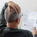 Mand har åbnet en regning og tager sig bekymret til hovedet