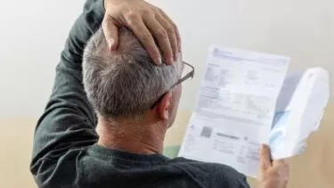 Mand har åbnet en regning og tager sig bekymret til hovedet