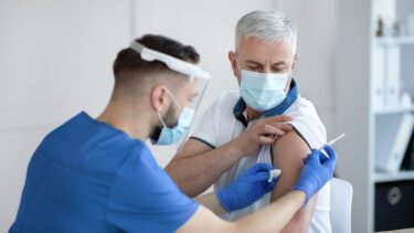 En ung læge giver en ældre mand en vaccine