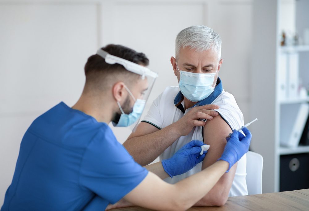En ung læge giver en ældre mand en vaccine