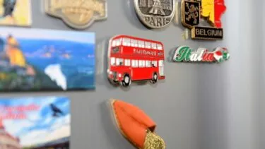Køleskabsmagneter, der illustrerer en rød bus, Eiffeltårnet i Paris, Italien og Belgien hænger på et køleskab
