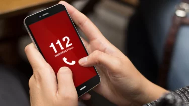 En telefon bliver holdt i hånden. Displayet viser, at der ringes til 1-1-2