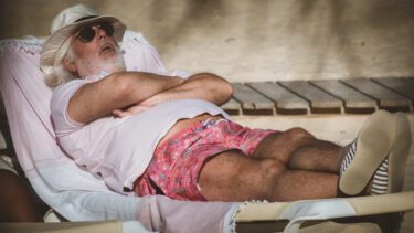 Foto af en ældre mand, der ligger og sover på en solstol