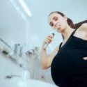 Foto af gravid kvinde, der børster tænder