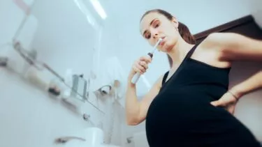 Foto af gravid kvinde, der børster tænder