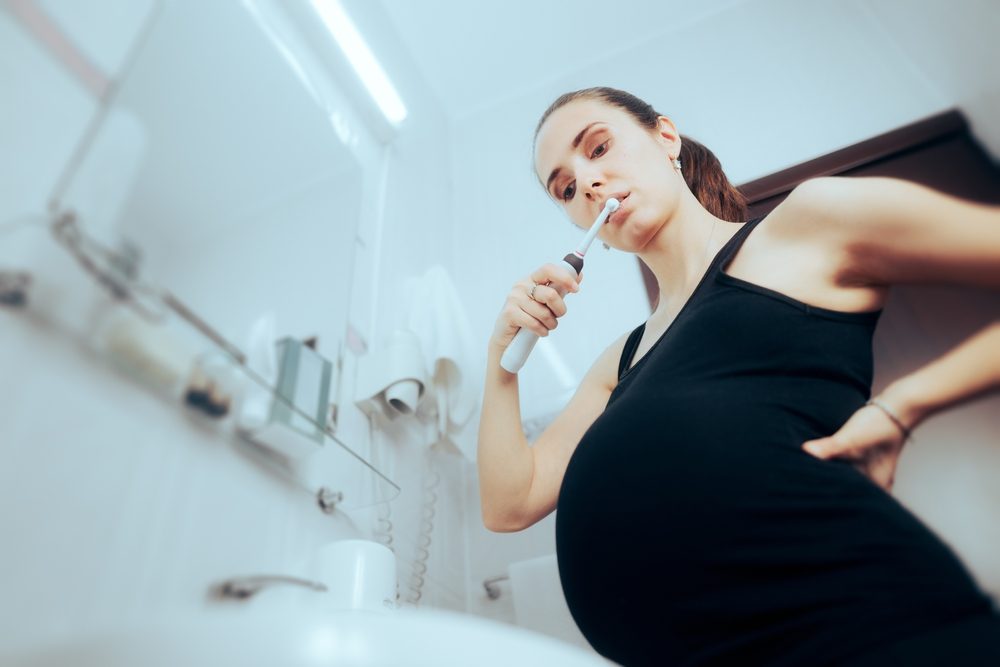 Foto af gravid kvinde, der børster tænder