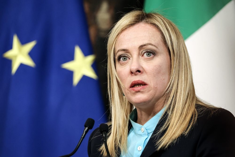 Italiens premierminister Georgia Meloni taler til en pressekonference i 2023 med et EU-flag i baggrunden.