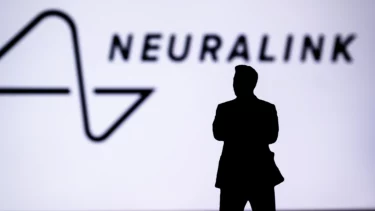 Elon Musk står foran en stor skærm, hvor der står "neuralink"