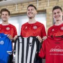 billede af tre spillere på det danske landshold i herrefodbold, der fremviser de nye EM-trøjer på et pressemøde.