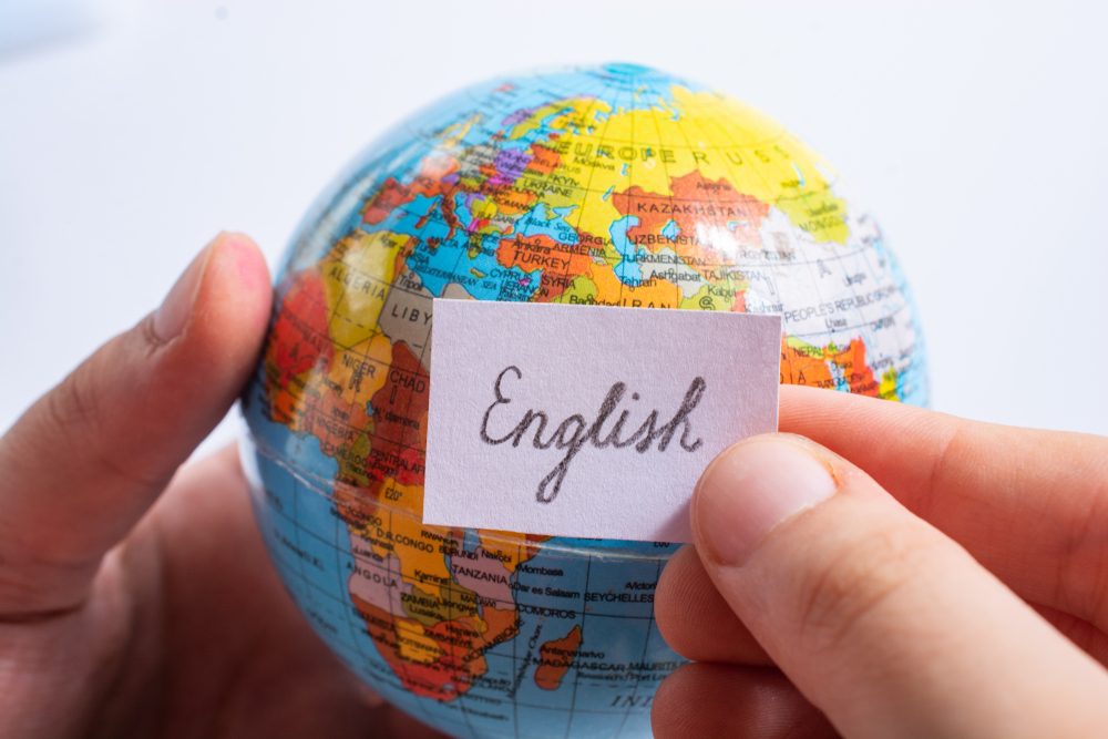 Person holder en globus med et skilt, hvorpå der står 'english