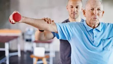 Gammel mand får hjælp af fysioterapeut