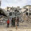 Palæstinensiske børn ser på en ødelagt bygning i byen Rafah