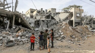 Palæstinensiske børn ser på en ødelagt bygning i byen Rafah