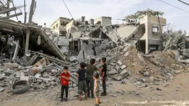 Palæstinensiske børn ser på en ødelagt bygning i byen Rafah