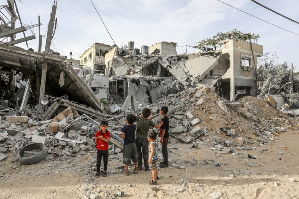 Palæstinensiske børn ser på en ødelagt bygning i byen Rafah