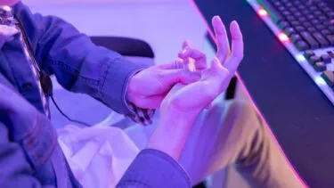 E-sport-udøver gnubber sin hånd, fordi han har ondt i den.