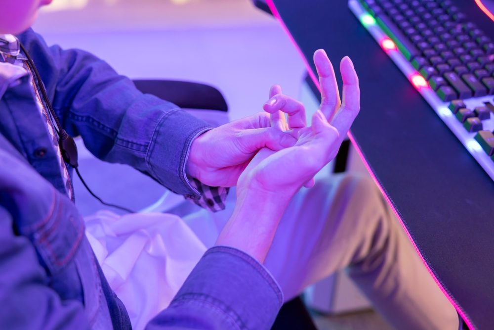 E-sport-udøver gnubber sin hånd, fordi han har ondt i den.