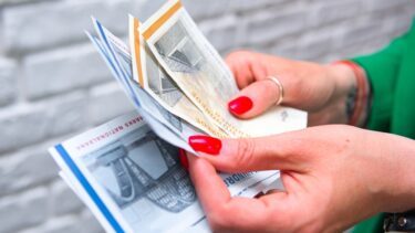 Kvindehænder med rød neglelak og fingerringe står med 500- og 100-kronesedler