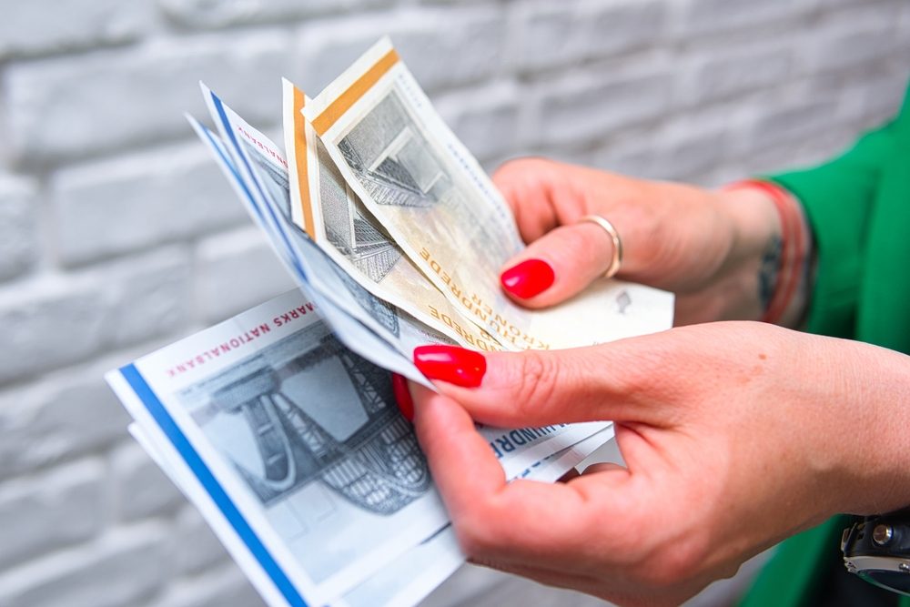 Kvindehænder med rød neglelak og fingerringe står med 500- og 100-kronesedler