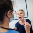 Kvinde får taget en oral DNA-test med en vatpind hos lægen