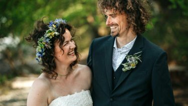 Brudeparret Rolf og Nina fra 'Gift ved første blik' smiler til hinanden. Hun er iført brudekjole og blomsterkrans i håret. Han er i jakkesæt og blomstret skjorte.