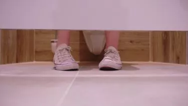 Fødder i en toiletbås, som man ser udefra