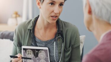 Læge peger på scanningsbillede af hjerne foran ældre kvindelig patient