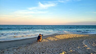 En fotograf tager billeder på en mennesketom strand helt ude ved vandet