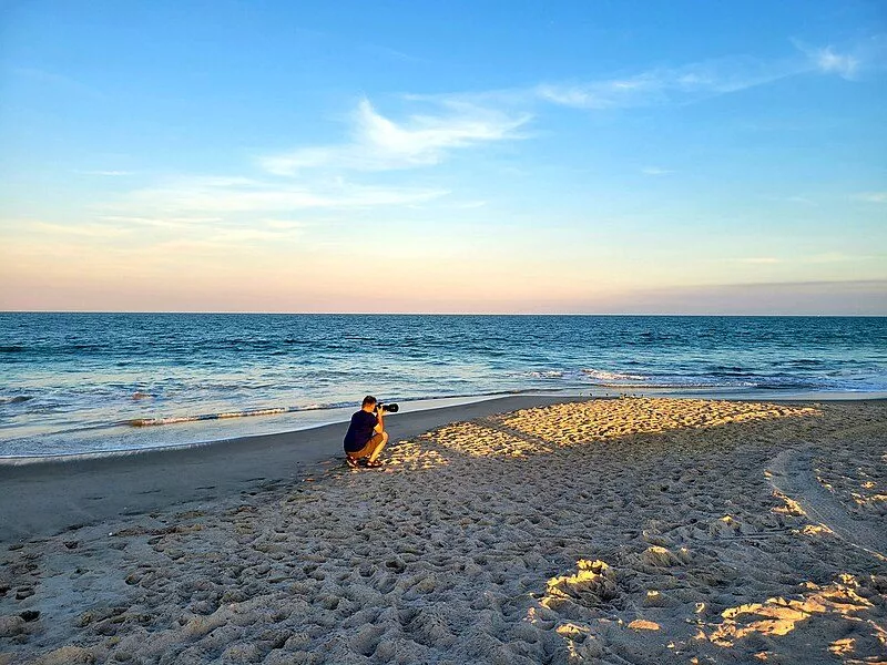 En fotograf tager billeder på en mennesketom strand helt ude ved vandet
