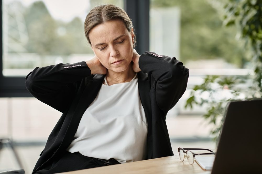 Kvinde sidder ved computer og holder sig i nakken