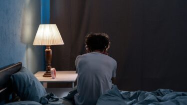Mand sidder med ryg til i sengen og ligner en, der ikke kan sove